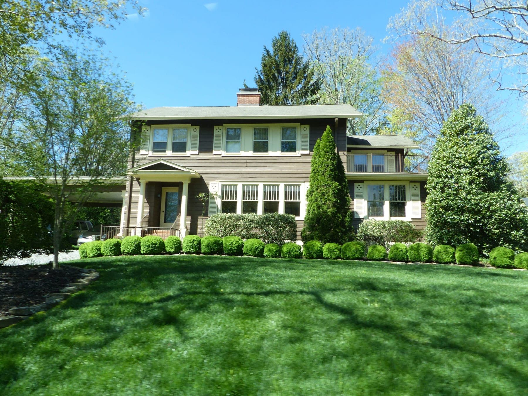 A two-storey shingled home set behind a manicured lawn and clipped boxwoods in Biltmore Forest, North Carolina