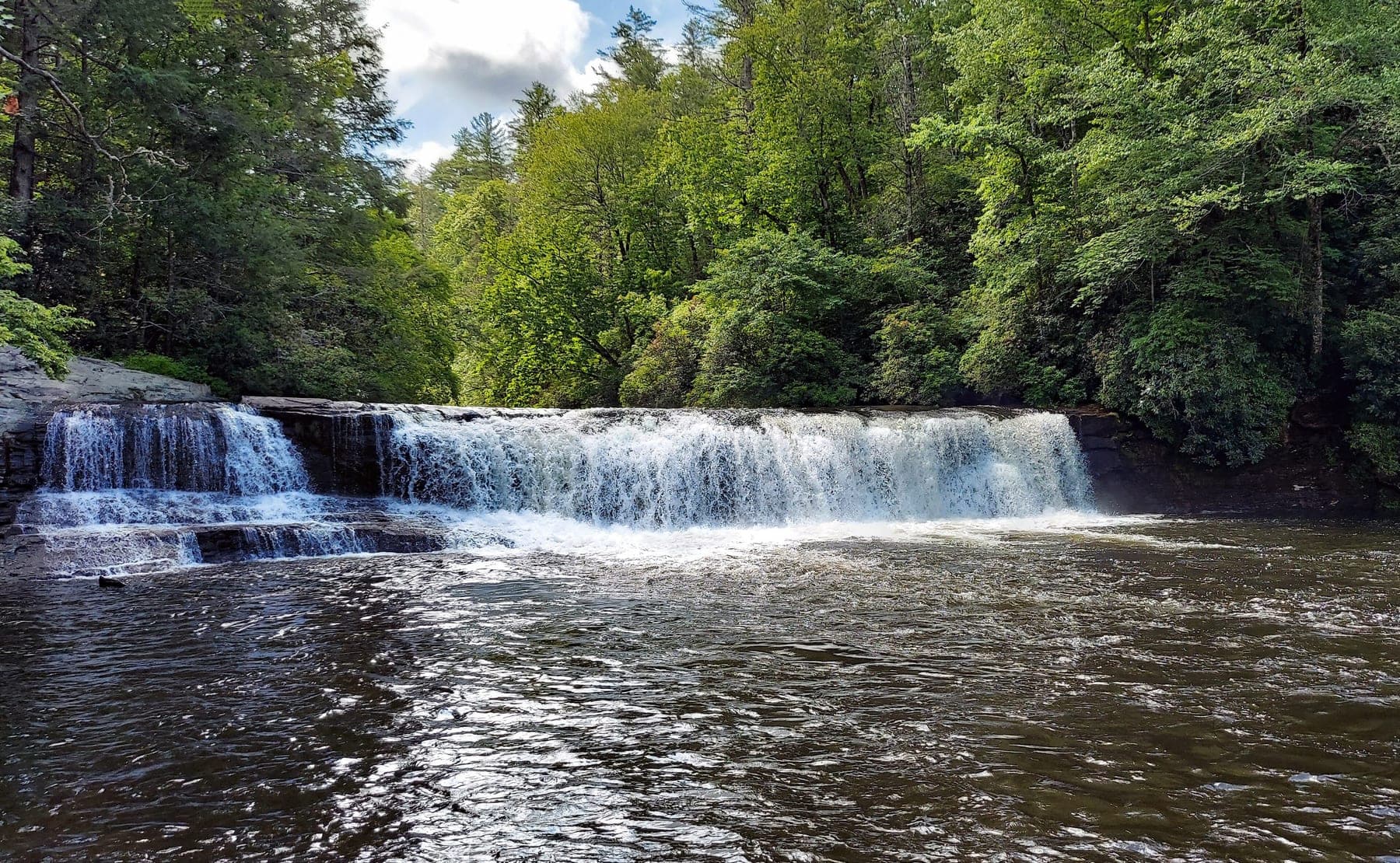 Hooker Falls on the Little River in DuPont State Recreational Forest, a wide low waterfall framed by summer forest