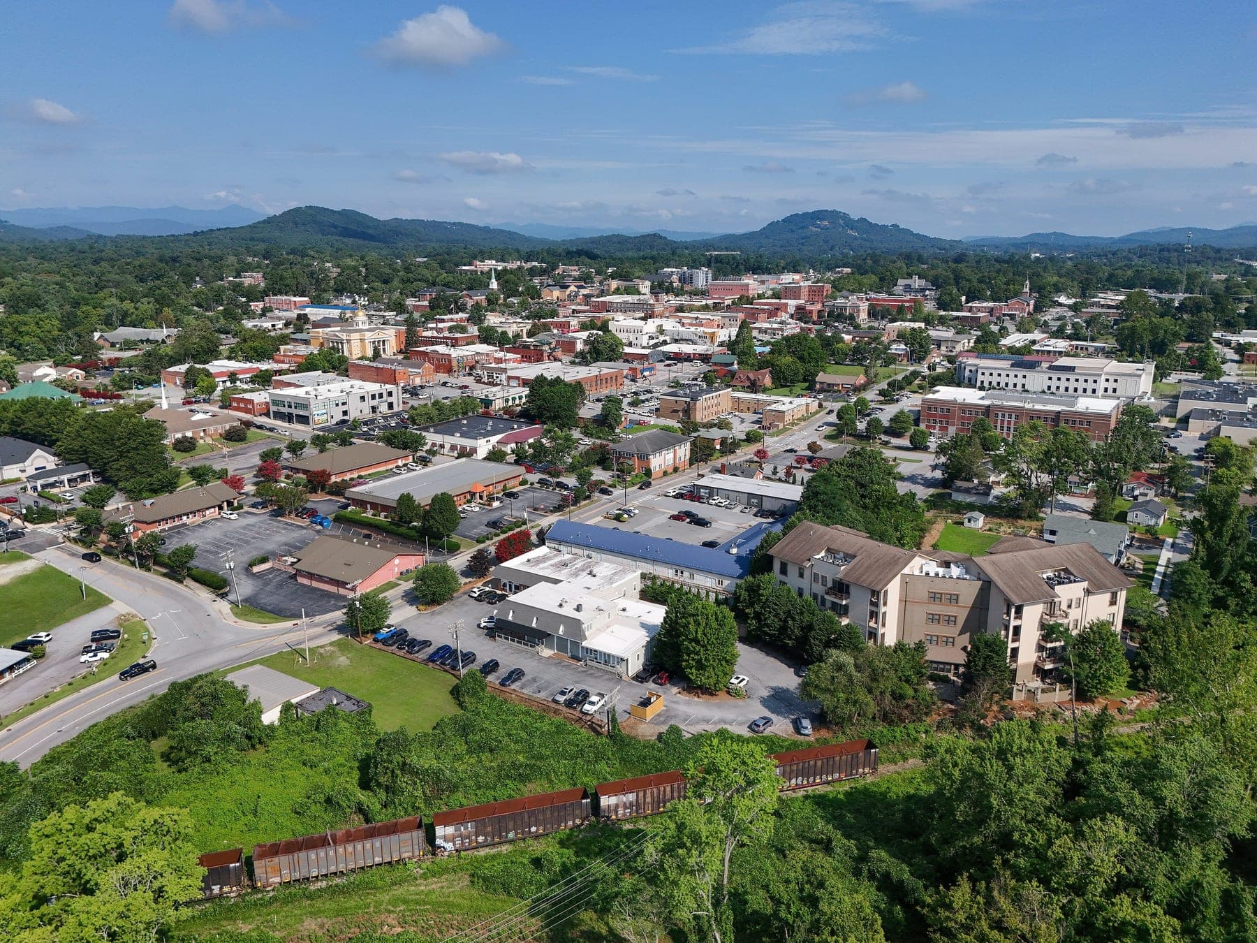 Aerial view of downtown Hendersonville, North Carolina, with tree-lined streets and the Blue Ridge Mountains on the horizon